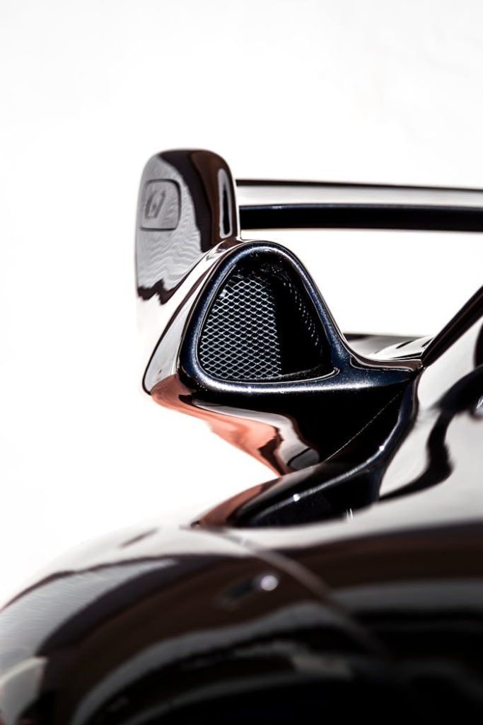 Detailed view of a black sports car rear wing showcasing sleek design and aerodynamics.